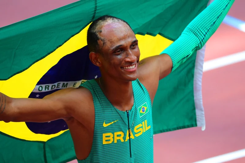 Alison dos Santos comemora com a bandeira do Brasil nas costas