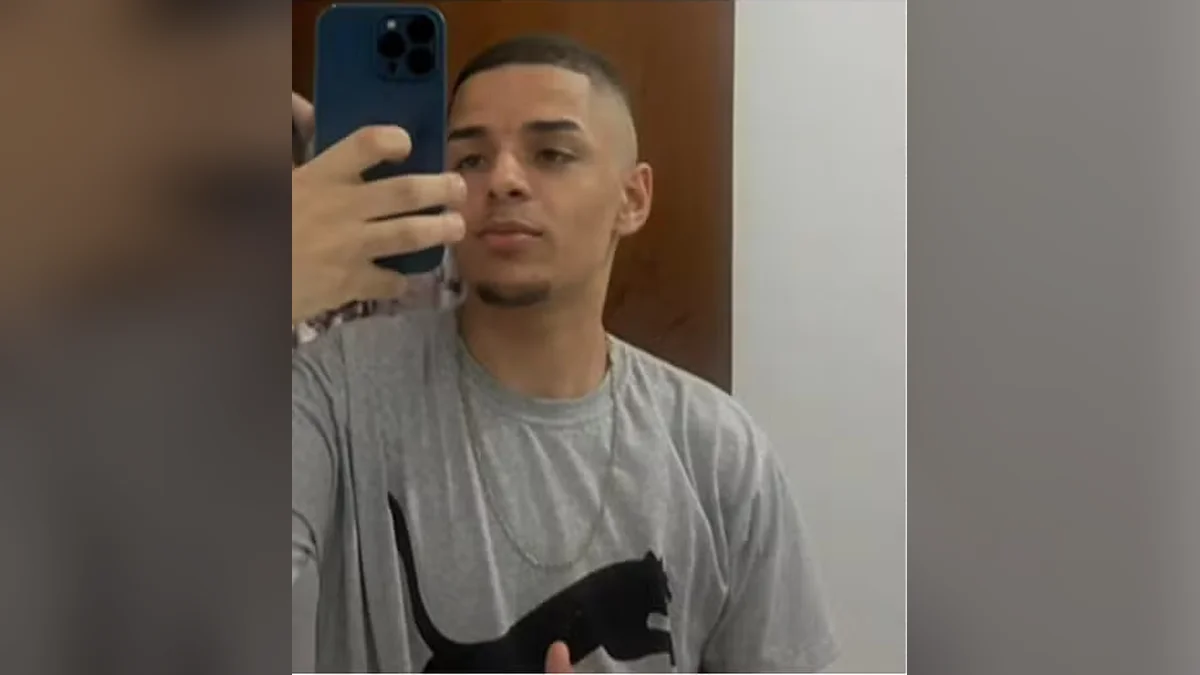 Gustavo Munis de Santana tira uma selfie no espelho, de camiseta cinza, segurando o celular