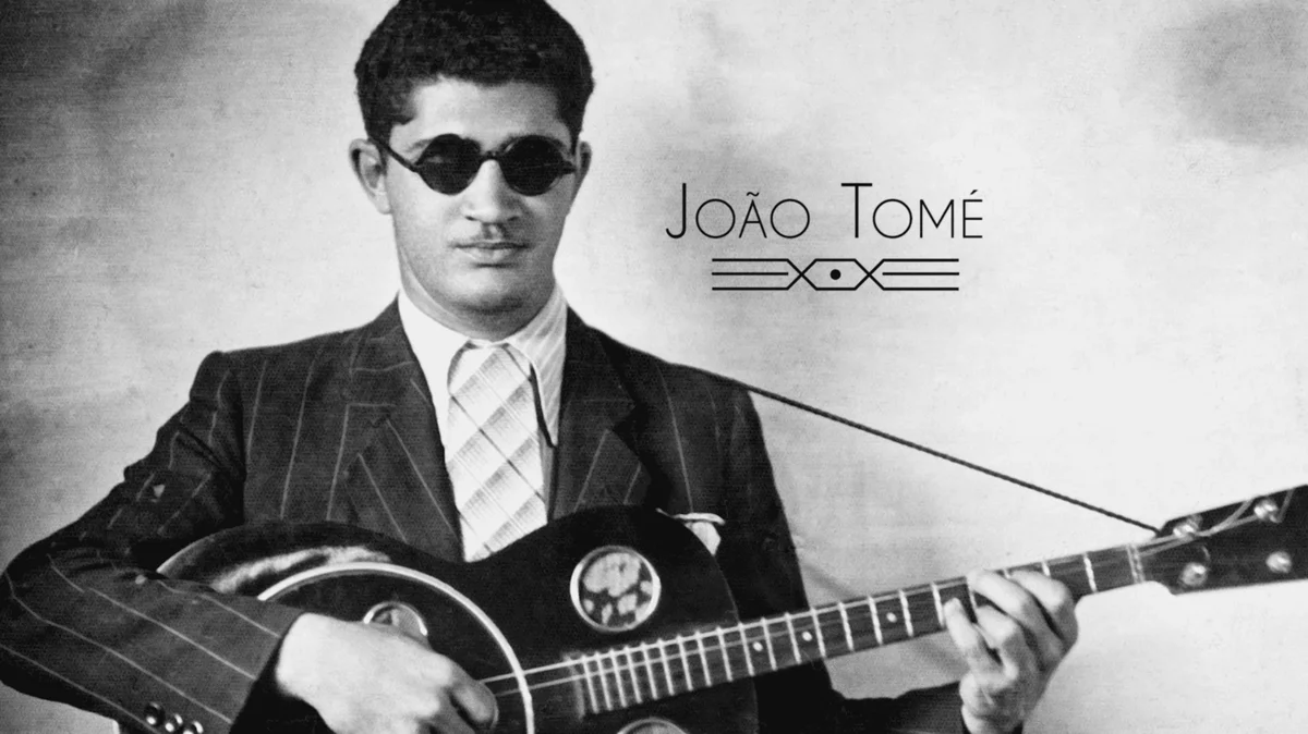 Retrato de arquivo de João Tomé, de óculos escuros, tocando violão, com o título do documentário Nem Todos Sabem