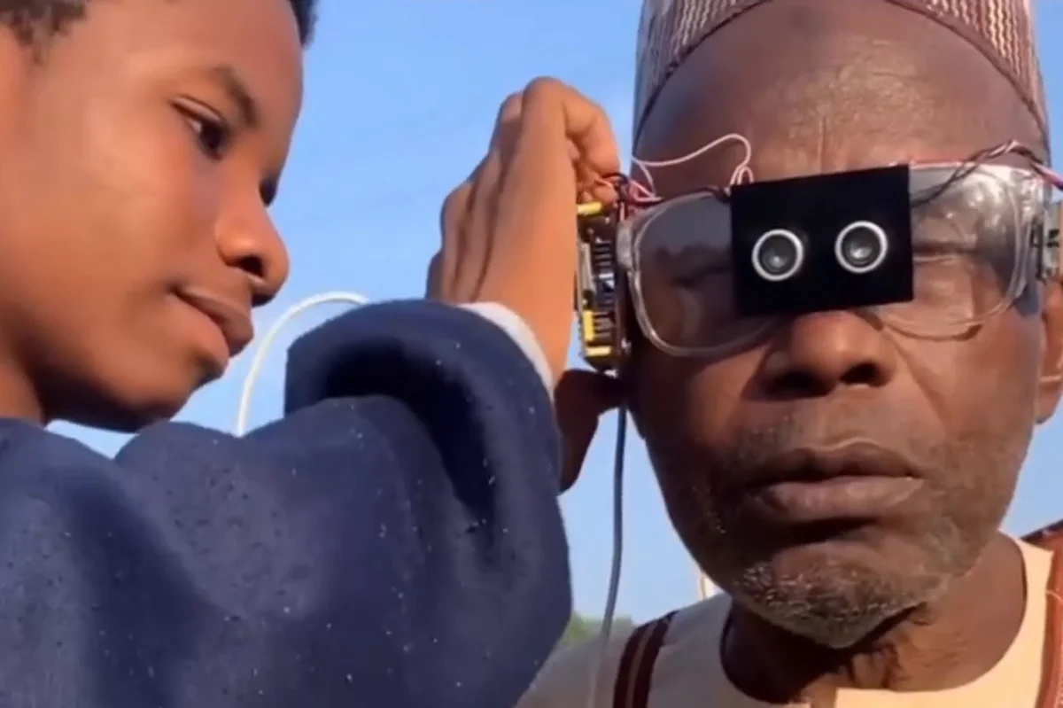 Khalifa Aminu ajusta óculos de inteligência artificial na cabeça de um homem mais velho, em Kano, na Nigéria