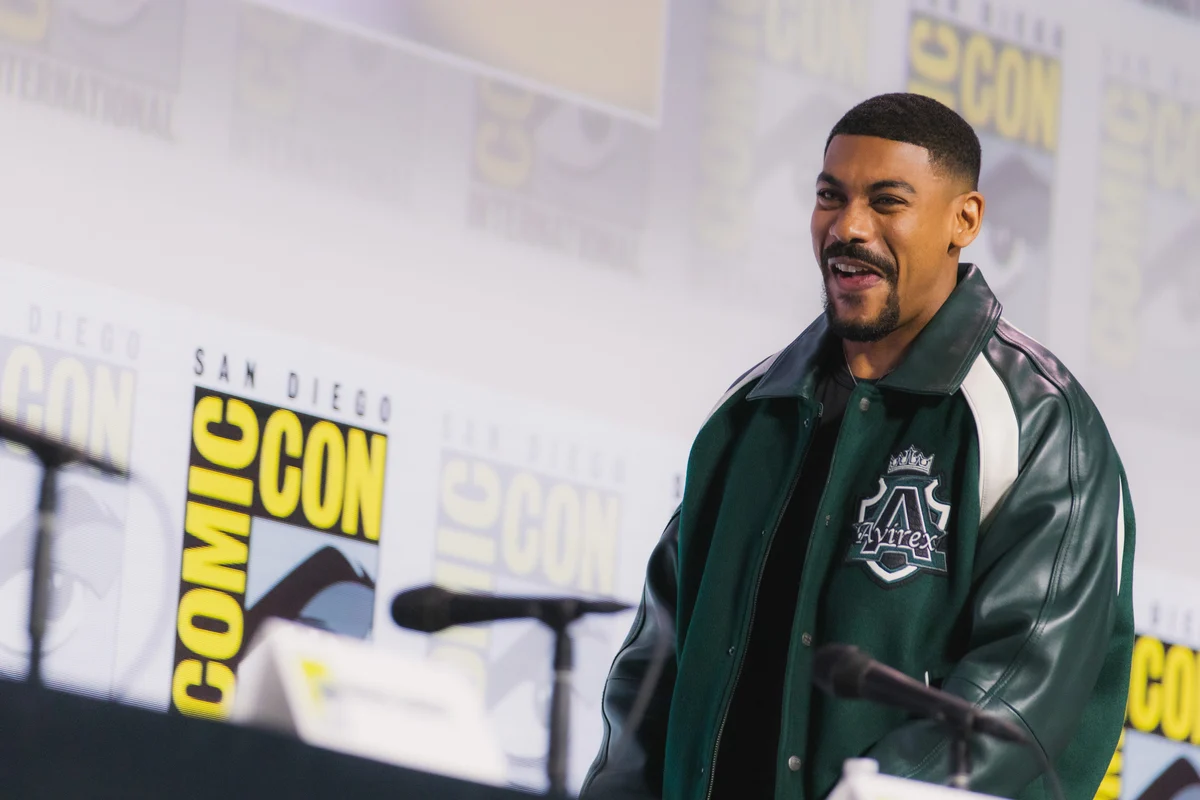 O ator Aaron Pierre em evento, de terno, sorrindo para o público