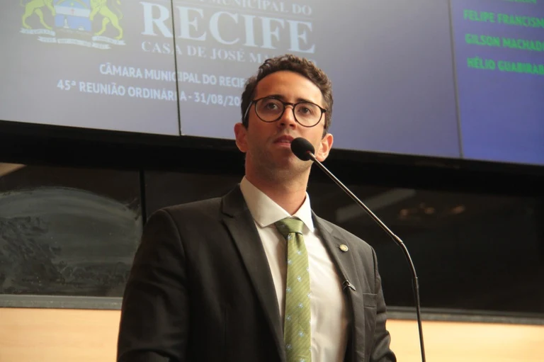 O vereador Thiago Medina, de terno escuro e gravata verde, discursa na tribuna da Câmara Municipal do Recife