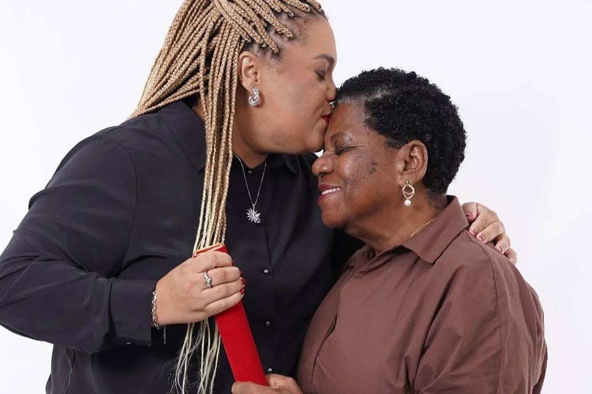 Mirtes Renata beija a testa da mãe, Marta Maria Santana, segurando o estojo do diploma