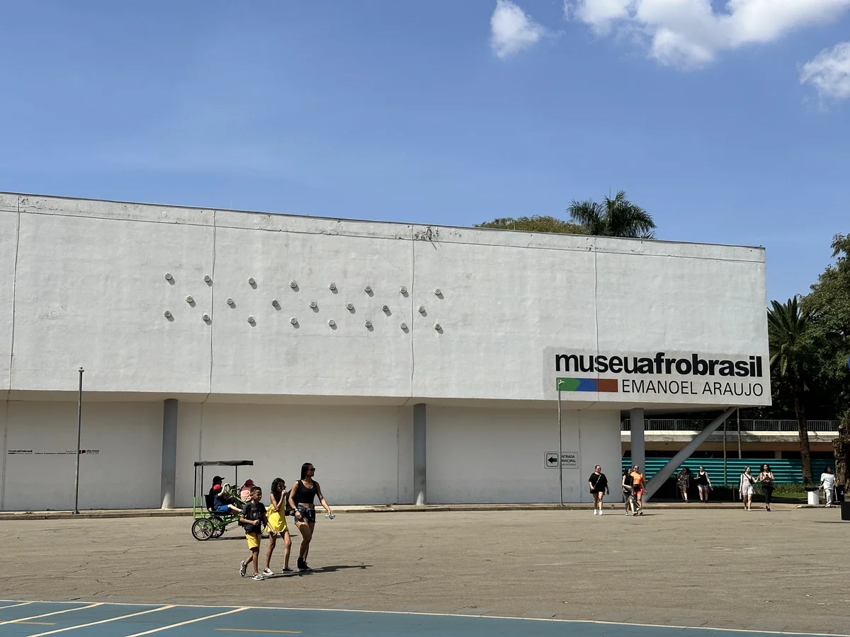 Fachada branca do Museu Afro Brasil com o letreiro museuafrobrasil Emanoel Araujo, sob c&eacute;u azul