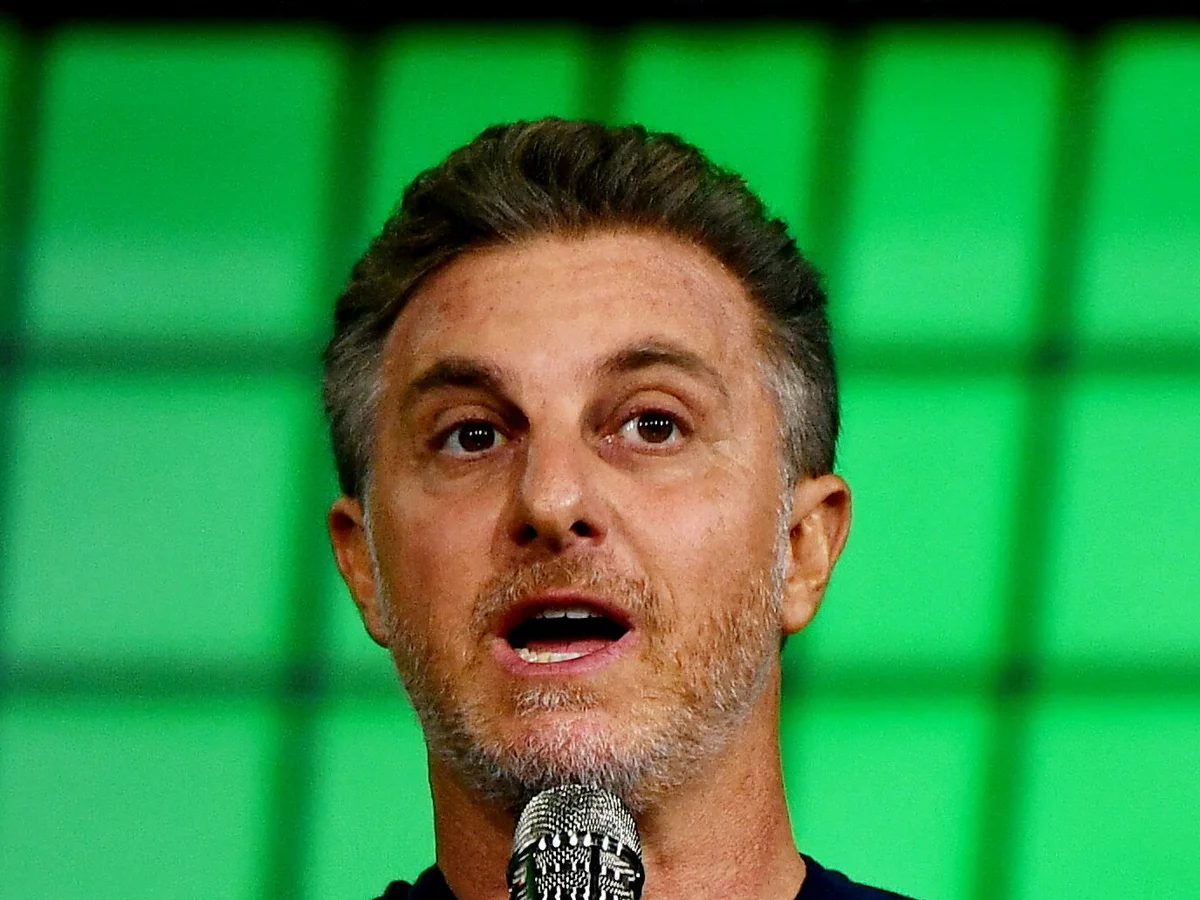 Luciano Huck fala ao microfone em um palco