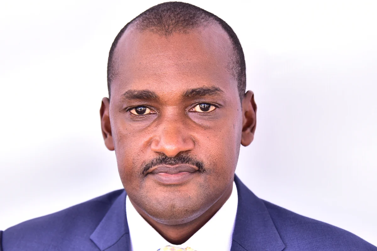Retrato oficial de Frank Tumwebaze, de terno azul, camisa branca e gravata